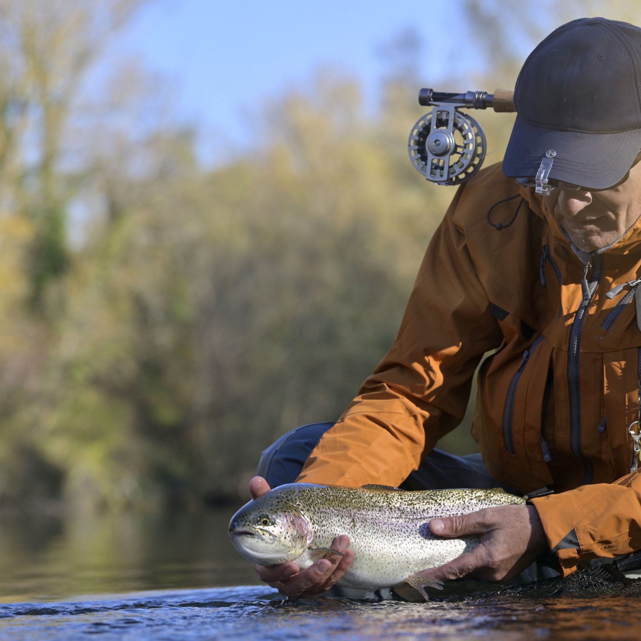 Oregon man holding rainbow trout in river